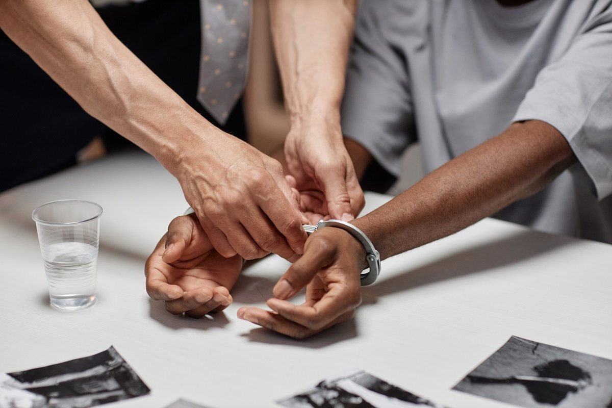 A close up on handcuffs being places on a suspects wrists by a law enforcement officer