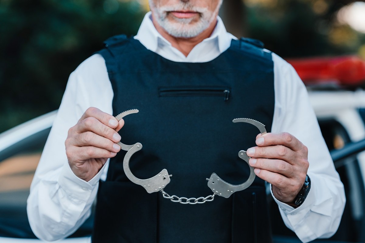 A police officer holding an open pair of handcuffs