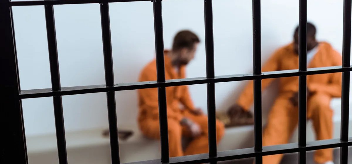 multiethnic prisoners playing chess behind prison bars