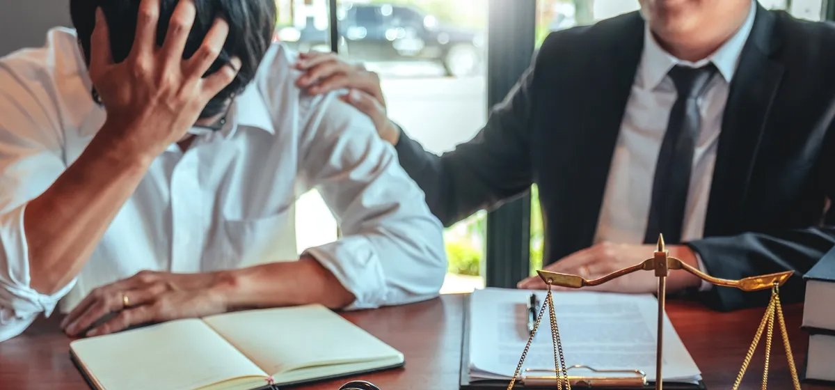 A lawyer resting his hand on the shoulder of a distressed client