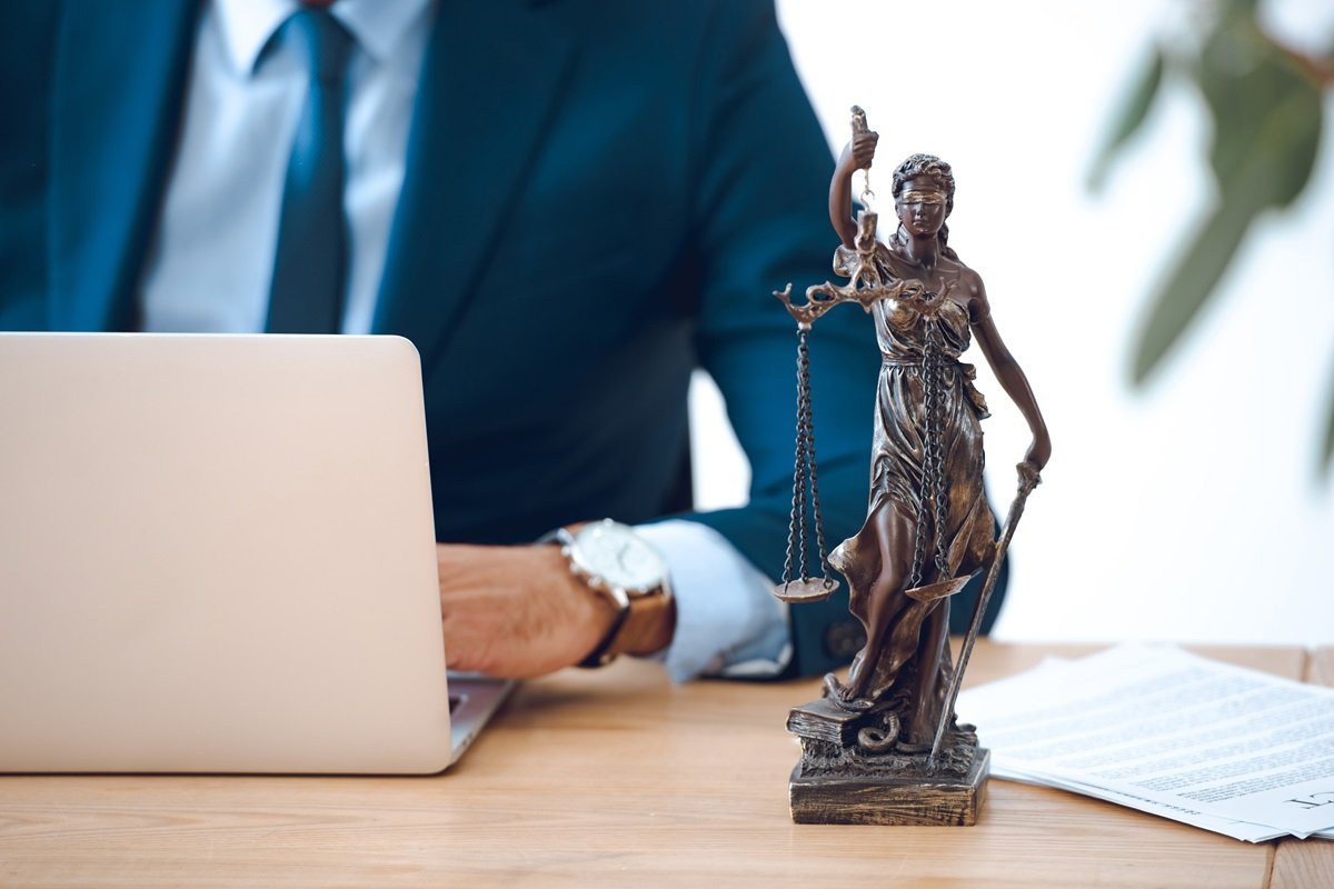 A lawyer working at a desk with a statuette of Lady Justice