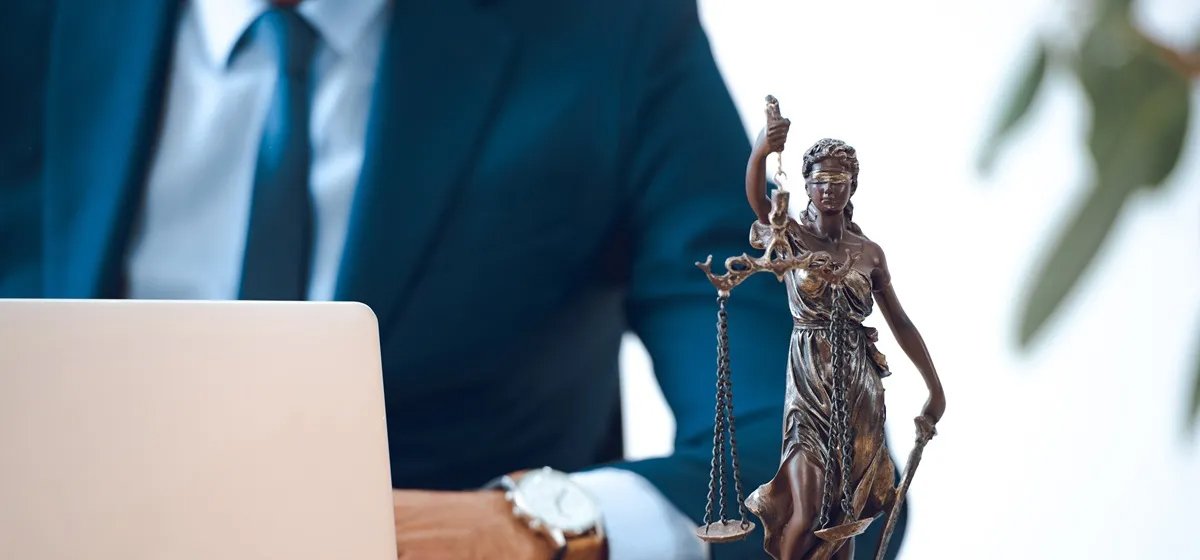 A lawyer working at a desk with a statuette of Lady Justice