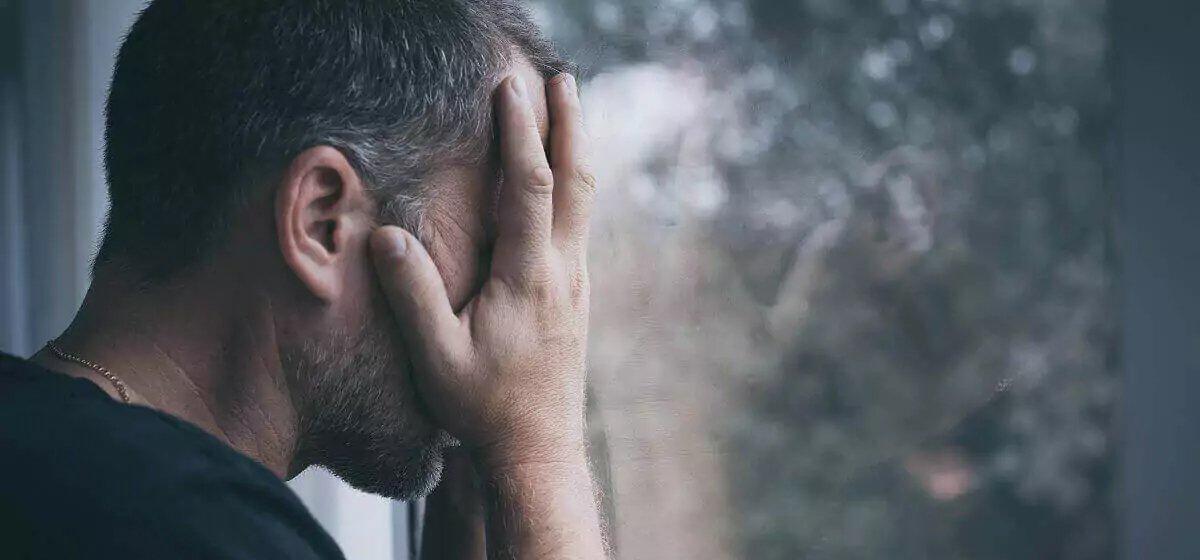 A sad man holding his face.