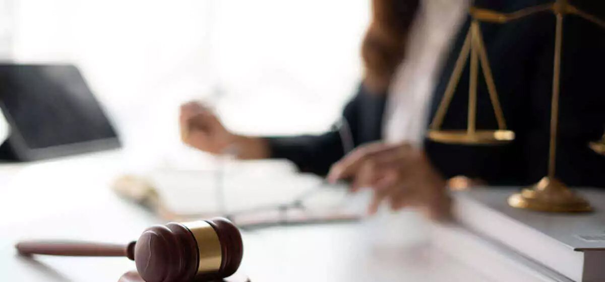 A gavel sitting on a desk in front of a lawyer.