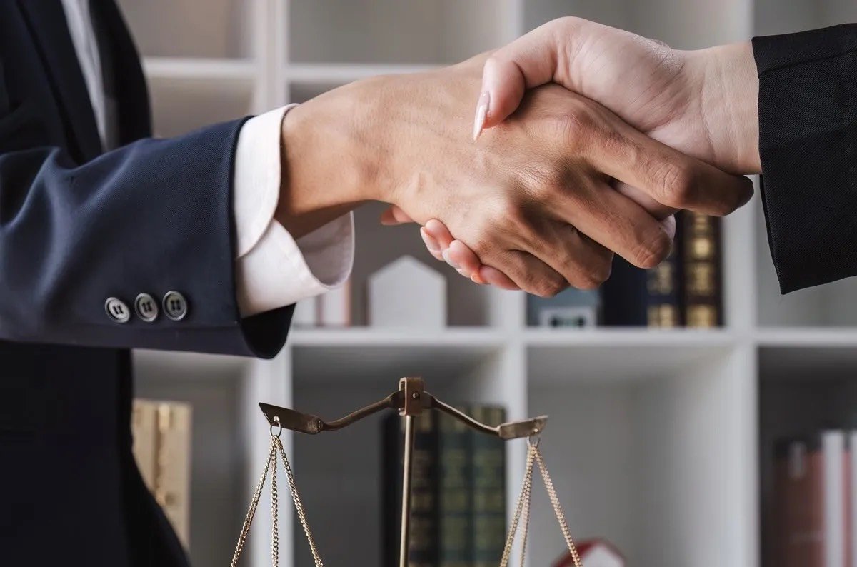 A lawyer and client shaking hands over a scale