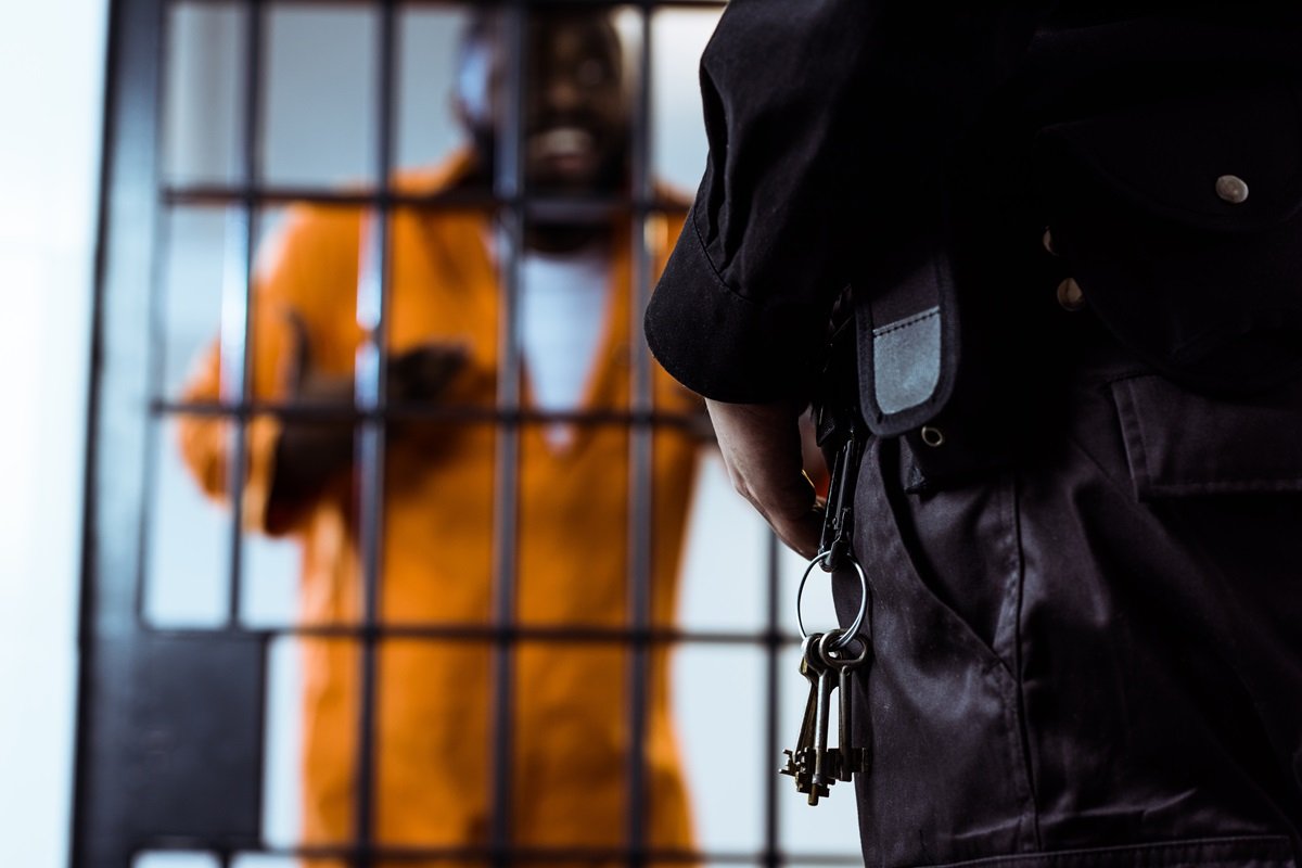 A guard standing outside an occupied jail cell