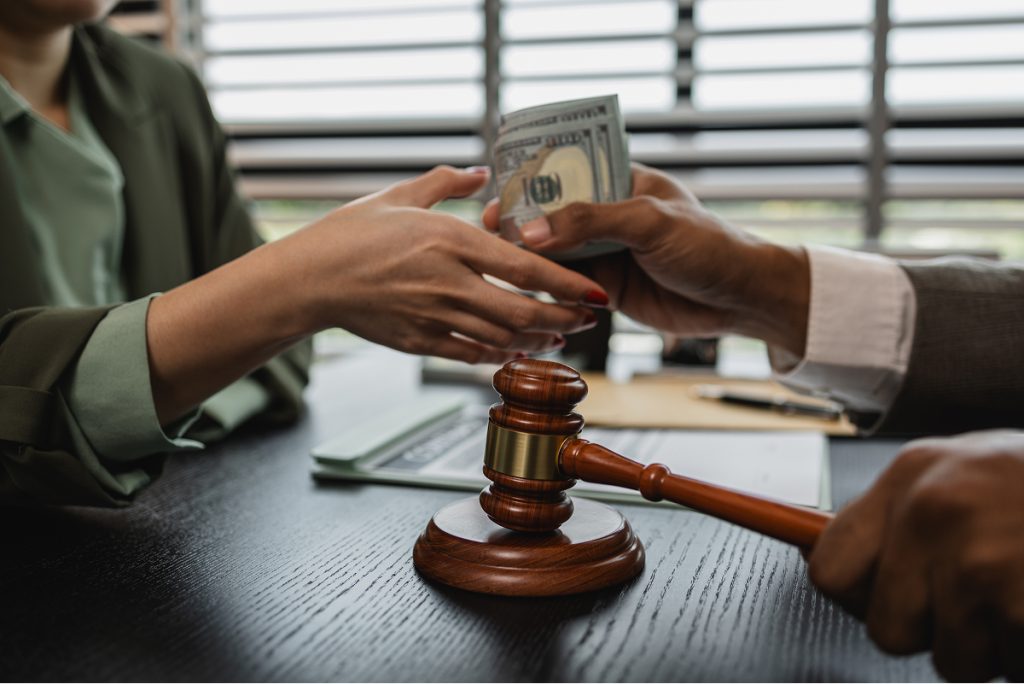 A judge handing someone cash while hitting a gavel