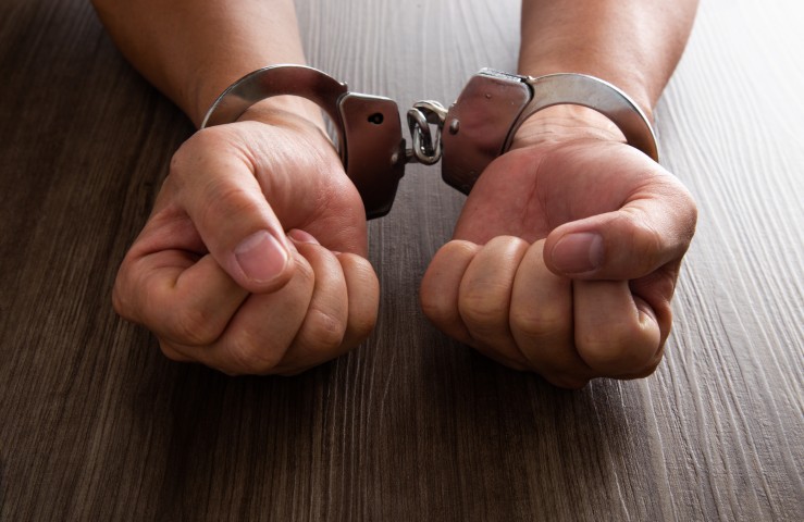 A person's hands on a table in handcuffs