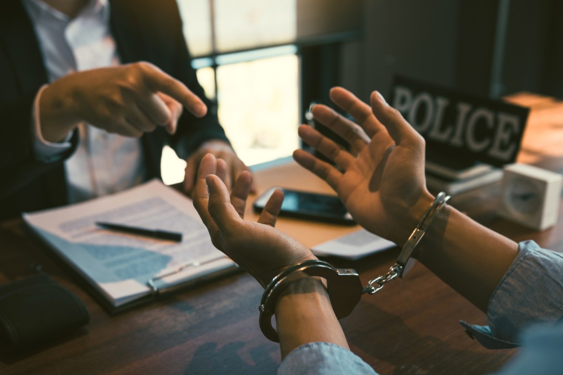 A man in handcuffs talking to a detective