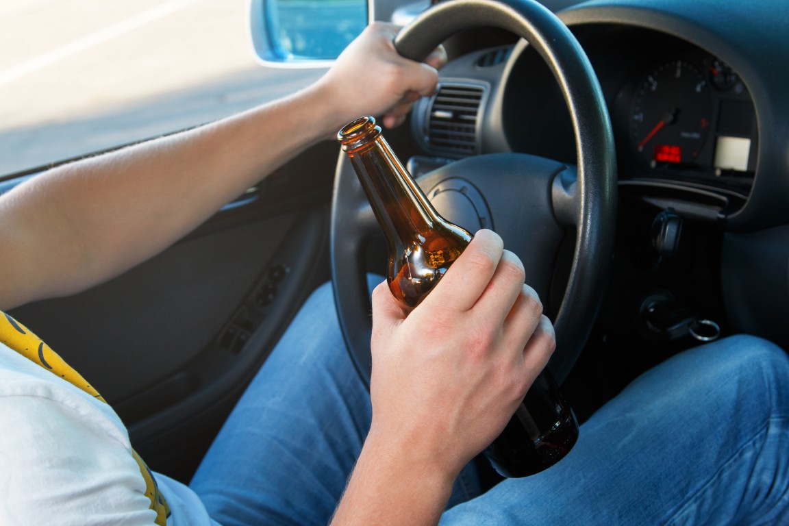 A man drinking a beer while driving